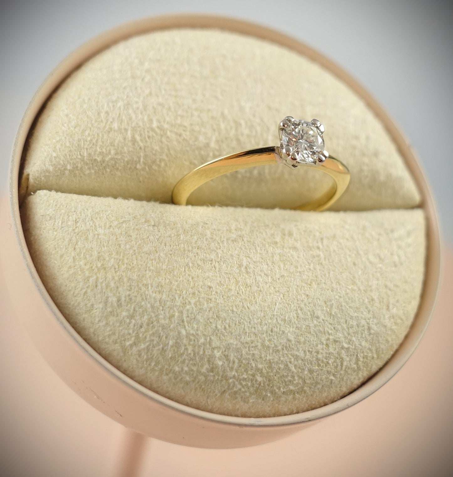 Der Ring 750 Gelbgold 0,43 ct Brillant Ringgröße 54 von Ninas Schmuckhandel wird auf einem beigen Kissen in einer runden rosa Schmuckschatulle präsentiert. Sein elegant geschliffener Diamant und das glatte Band in SI-Qualität unterstreichen die Brillanz des Steins.