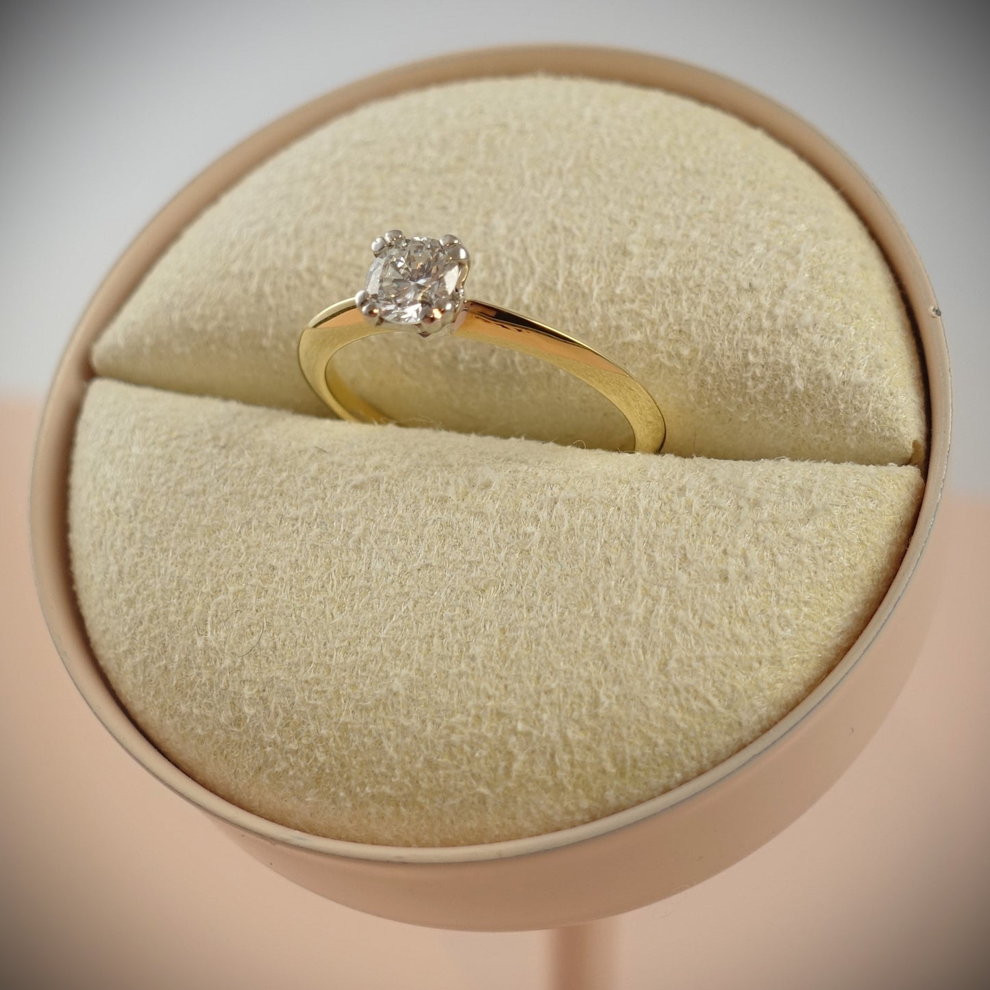 Ein Ring aus 750 Gelbgold mit 0,43 ct Diamant im Kissenschliff von Ninas Schmuckhandel wird elegant in einer runden, beigefarbenen Box präsentiert, Ringgröße 54.