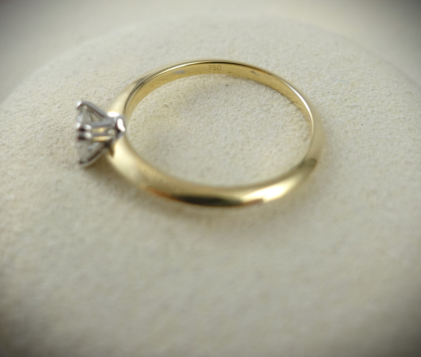 Der Ring 750 Gelbgold von Ninas Schmuckhandel verfügt über einen Brillanten von 0,43 ct in einer Krappenfassung auf einem gravierten 18-karätigen Goldband mit SI-Qualität und ruht auf einer weichen beigen Oberfläche.